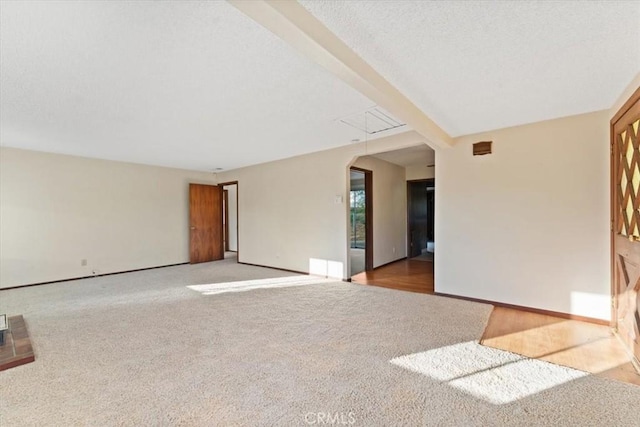 unfurnished living room featuring baseboards, attic access, and carpet