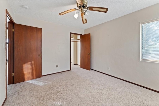 unfurnished bedroom featuring carpet, baseboards, a textured ceiling, and ceiling fan