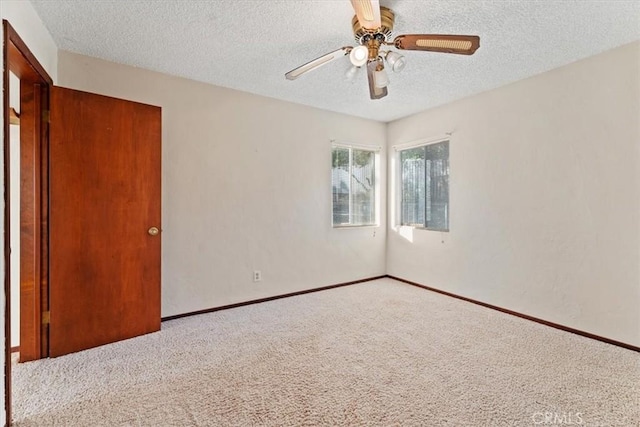 spare room featuring carpet floors, baseboards, a ceiling fan, and a textured ceiling