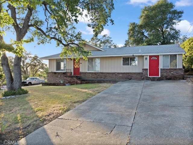 ranch-style house featuring a front yard, brick siding, and board and batten siding