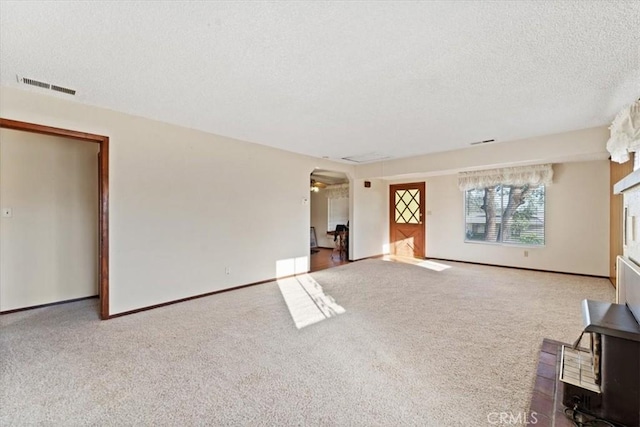 unfurnished living room with carpet, visible vents, and a textured ceiling