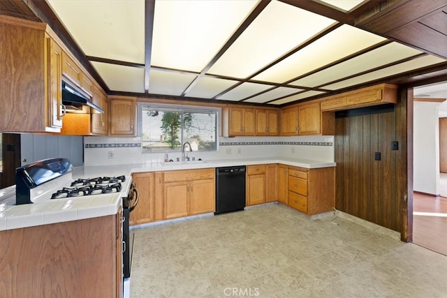 kitchen with sink, gas range gas stove, extractor fan, tile counters, and black dishwasher