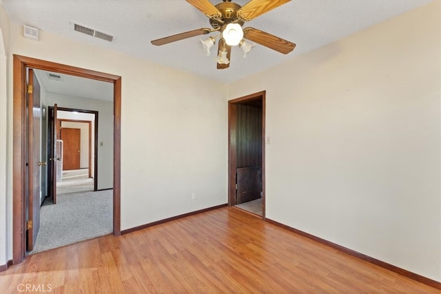 unfurnished room with light hardwood / wood-style flooring, ceiling fan, and a textured ceiling