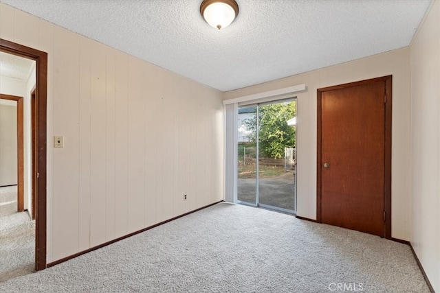 unfurnished bedroom featuring access to outside, a textured ceiling, and light carpet