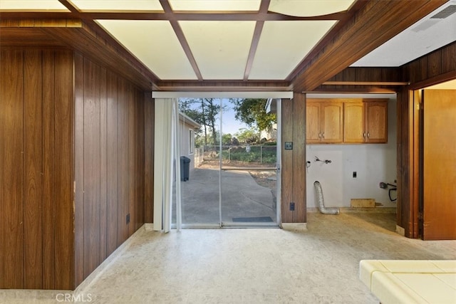 doorway featuring beam ceiling and wooden walls