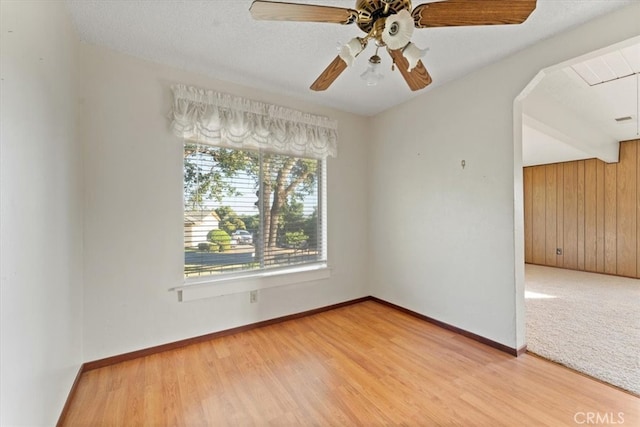 spare room featuring wooden walls, ceiling fan, and hardwood / wood-style flooring