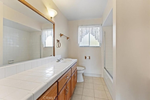 full bath with toilet, tile patterned floors, plenty of natural light, and vanity