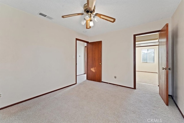 unfurnished bedroom featuring ceiling fan, light colored carpet, and a textured ceiling