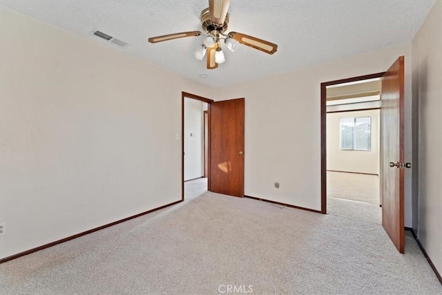unfurnished bedroom with a ceiling fan, a textured ceiling, carpet, and visible vents
