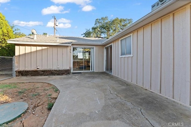exterior space featuring board and batten siding, fence, and a patio area