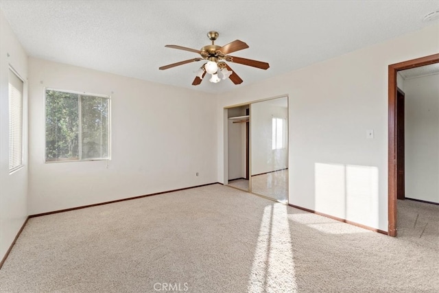 unfurnished bedroom with a textured ceiling, ceiling fan, light colored carpet, and a closet