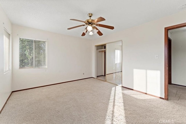 unfurnished bedroom with ceiling fan, a closet, carpet flooring, and baseboards