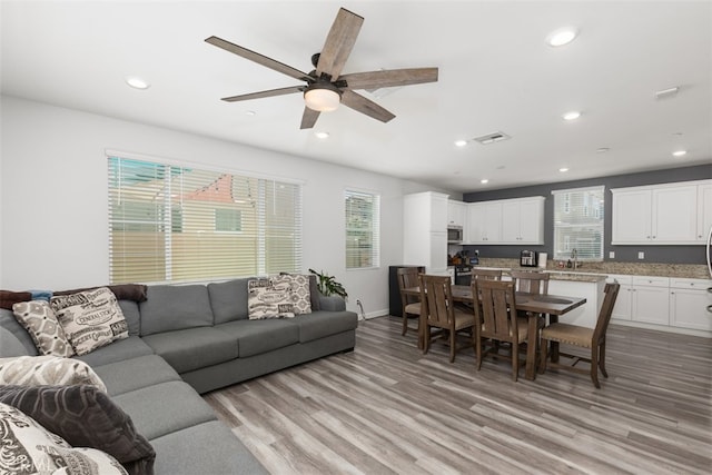 living room featuring light hardwood / wood-style flooring, ceiling fan, and sink