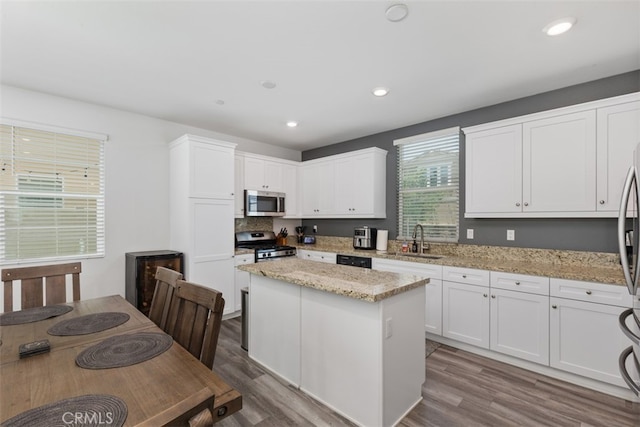 kitchen with appliances with stainless steel finishes, sink, a kitchen island, and wood-type flooring