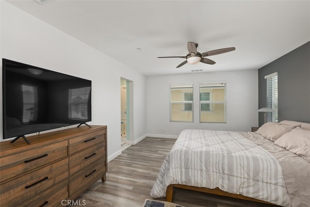 bedroom featuring hardwood / wood-style flooring, ceiling fan, and ensuite bath