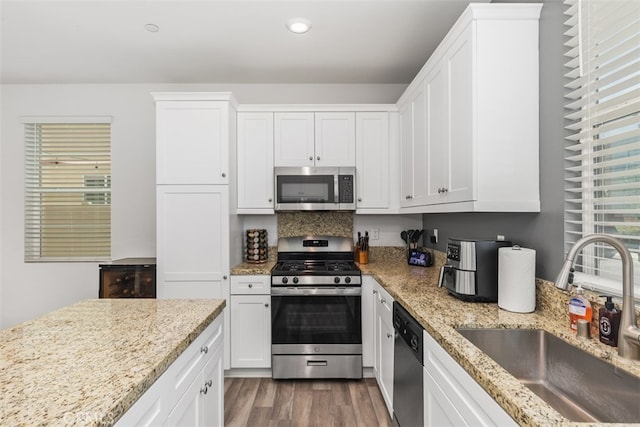 kitchen featuring light stone countertops, white cabinetry, sink, dark wood-type flooring, and stainless steel appliances