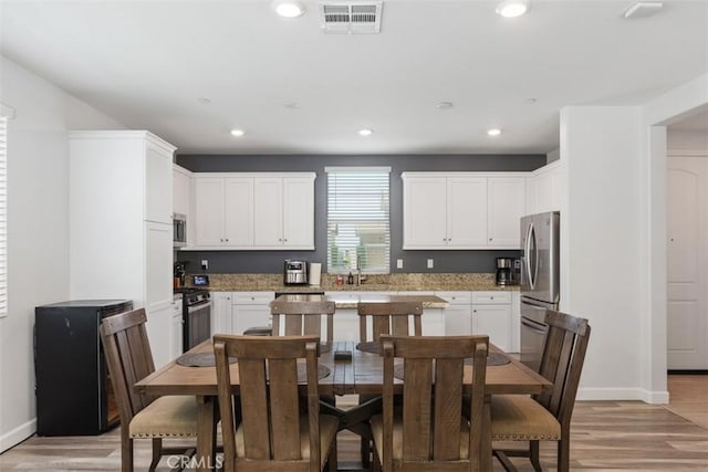 kitchen featuring white cabinetry, light hardwood / wood-style flooring, light stone counters, and appliances with stainless steel finishes