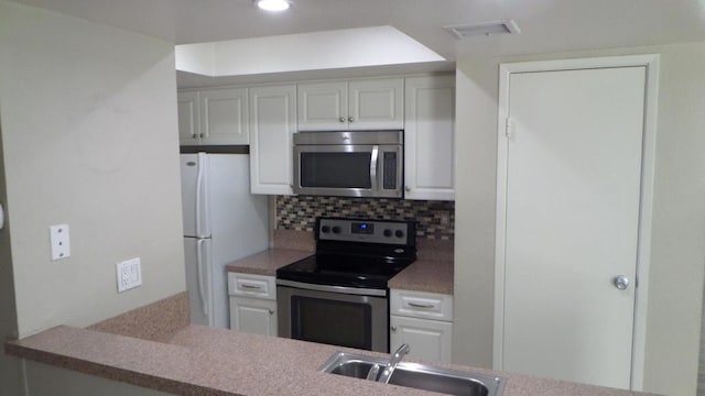 kitchen with tasteful backsplash, white cabinetry, sink, and appliances with stainless steel finishes