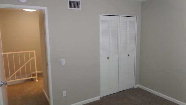 unfurnished bedroom featuring a closet and dark carpet