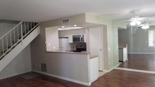 kitchen featuring kitchen peninsula, dark wood-type flooring, white cabinets, and stainless steel appliances