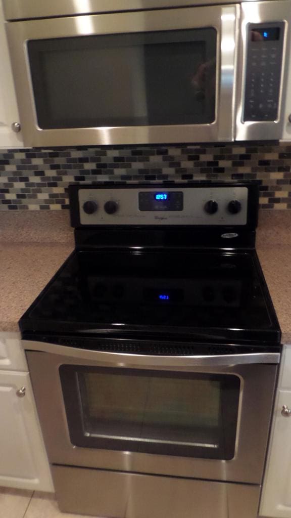 kitchen with white cabinets, decorative backsplash, and appliances with stainless steel finishes