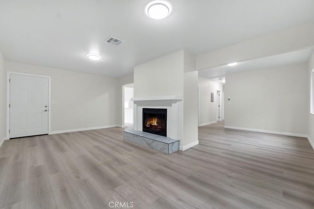 unfurnished living room featuring a tiled fireplace and light hardwood / wood-style floors