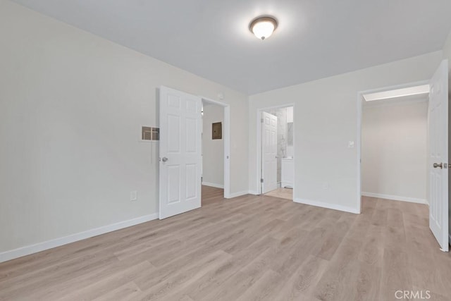 unfurnished bedroom with ensuite bath, a closet, and light hardwood / wood-style flooring