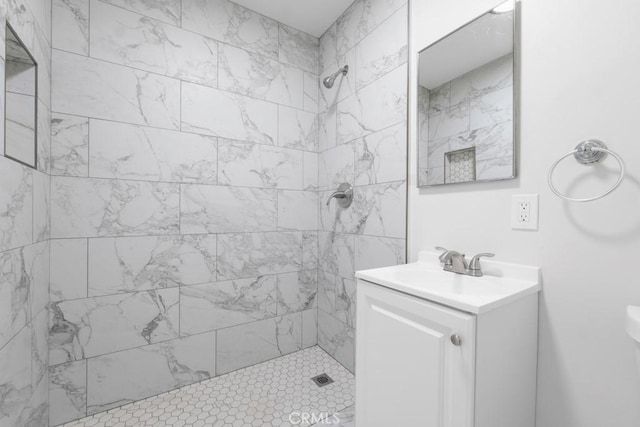 bathroom with a tile shower and vanity