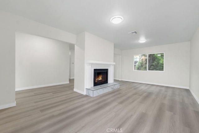 unfurnished living room featuring a tiled fireplace and light hardwood / wood-style flooring