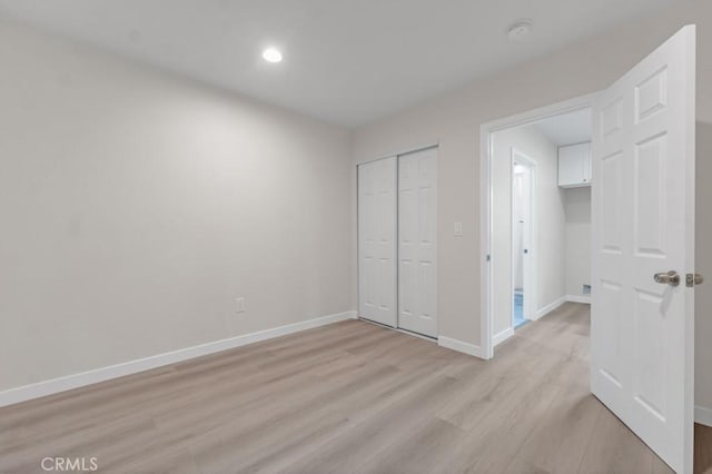 unfurnished bedroom featuring light hardwood / wood-style flooring and a closet