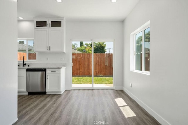 kitchen with white cabinets, dishwasher, light wood-type flooring, and a wealth of natural light