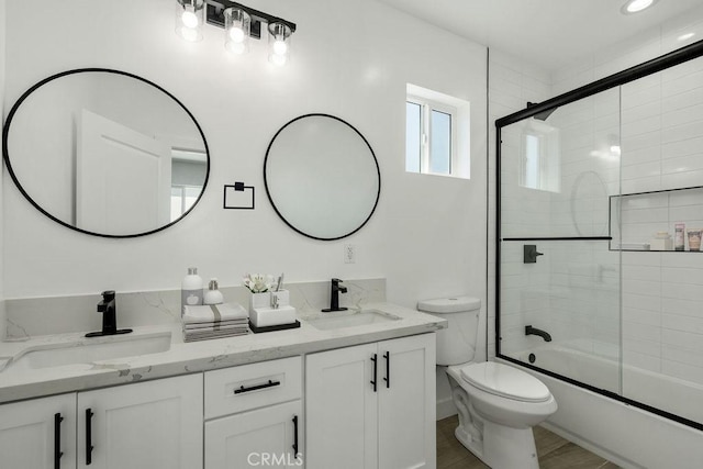 full bathroom featuring combined bath / shower with glass door, hardwood / wood-style floors, vanity, and toilet