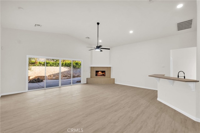 unfurnished living room featuring light hardwood / wood-style floors, vaulted ceiling, and ceiling fan