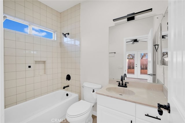 full bathroom featuring ceiling fan, french doors, toilet, vanity, and tiled shower / bath