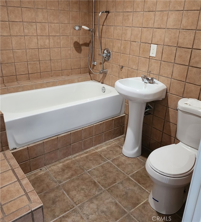 bathroom featuring toilet, tile patterned floors, tiled shower / bath combo, and tile walls