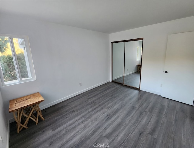 unfurnished bedroom featuring a closet and dark wood-type flooring