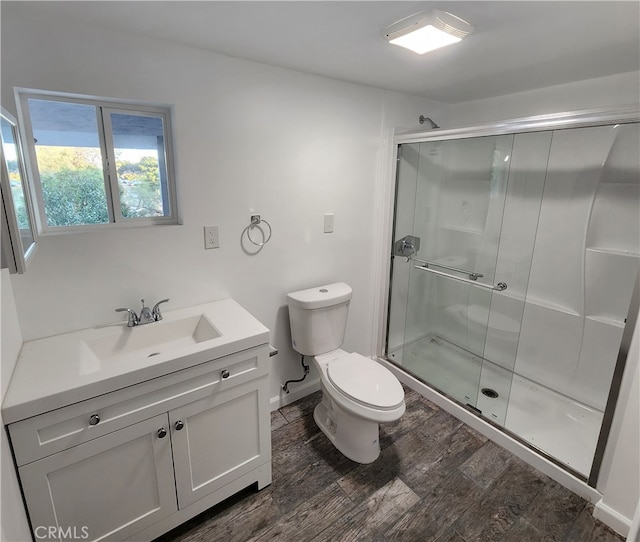 bathroom featuring a shower with door, vanity, hardwood / wood-style flooring, and toilet