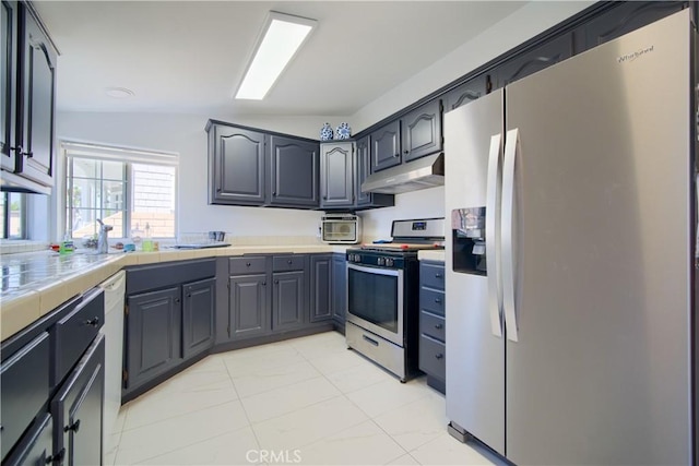 kitchen featuring tile countertops, appliances with stainless steel finishes, and vaulted ceiling