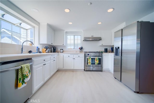 kitchen with sink, stainless steel appliances, tile countertops, light hardwood / wood-style floors, and white cabinets