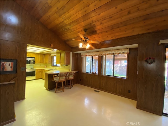 kitchen featuring lofted ceiling, kitchen peninsula, wood walls, white range oven, and ceiling fan