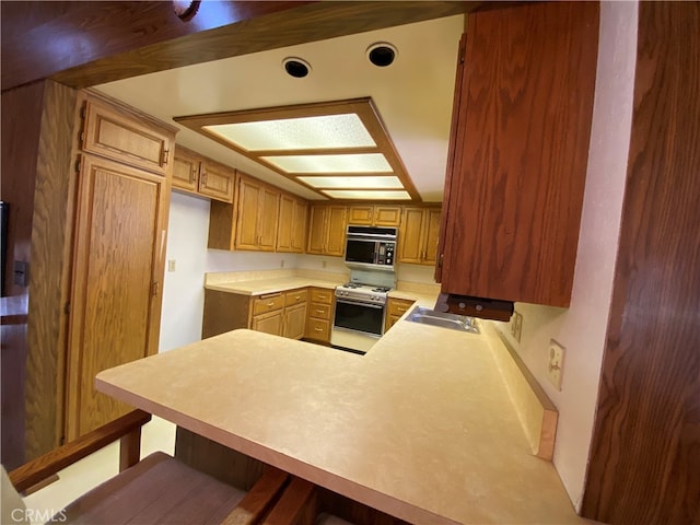 kitchen featuring white gas range, kitchen peninsula, and a kitchen bar