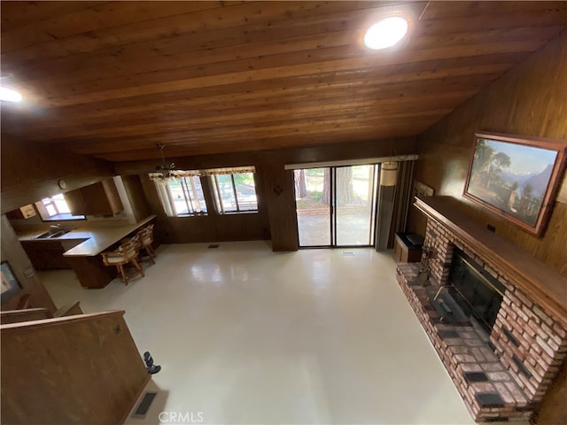 unfurnished living room with a brick fireplace, wood ceiling, vaulted ceiling, and concrete flooring