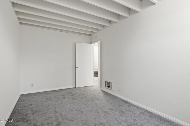 carpeted spare room with beamed ceiling