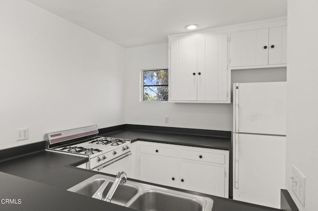 kitchen with white fridge, gas stove, white cabinetry, and sink