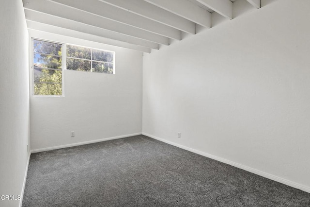 carpeted empty room with beam ceiling