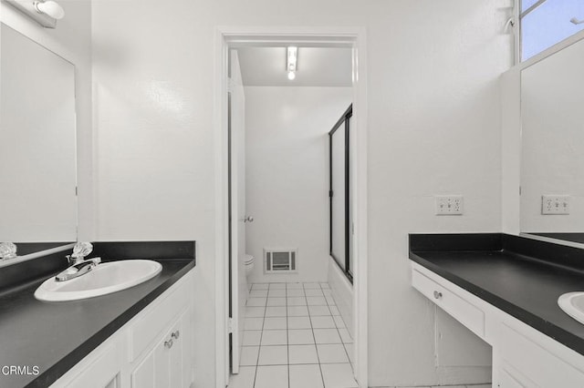 full bathroom with tile patterned floors, vanity, bath / shower combo with glass door, and toilet