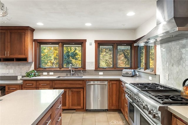 kitchen with appliances with stainless steel finishes, backsplash, sink, wall chimney range hood, and light tile patterned floors