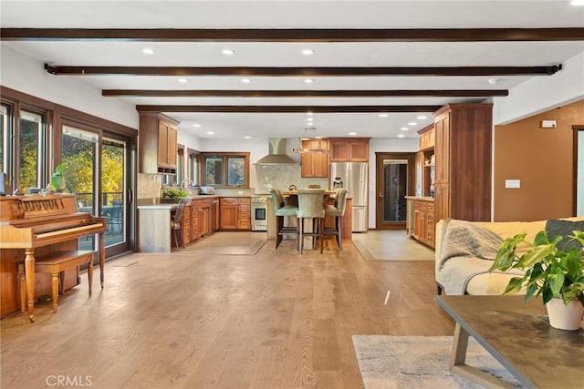 living room featuring beam ceiling, light wood-type flooring, and sink