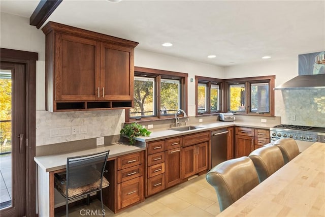 kitchen with backsplash, sink, stainless steel dishwasher, and wall chimney range hood