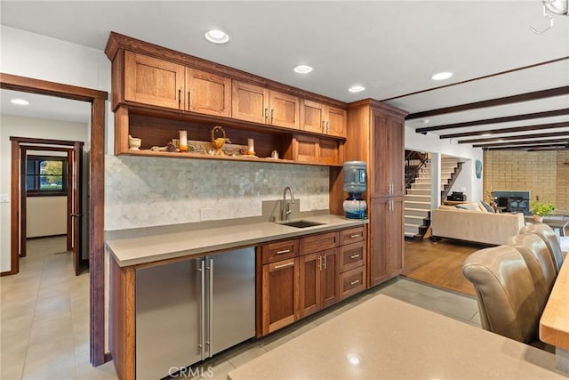 kitchen with beamed ceiling, light tile patterned floors, decorative backsplash, and sink